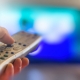 Close up of remote in hand with shallow depth of field during television watching