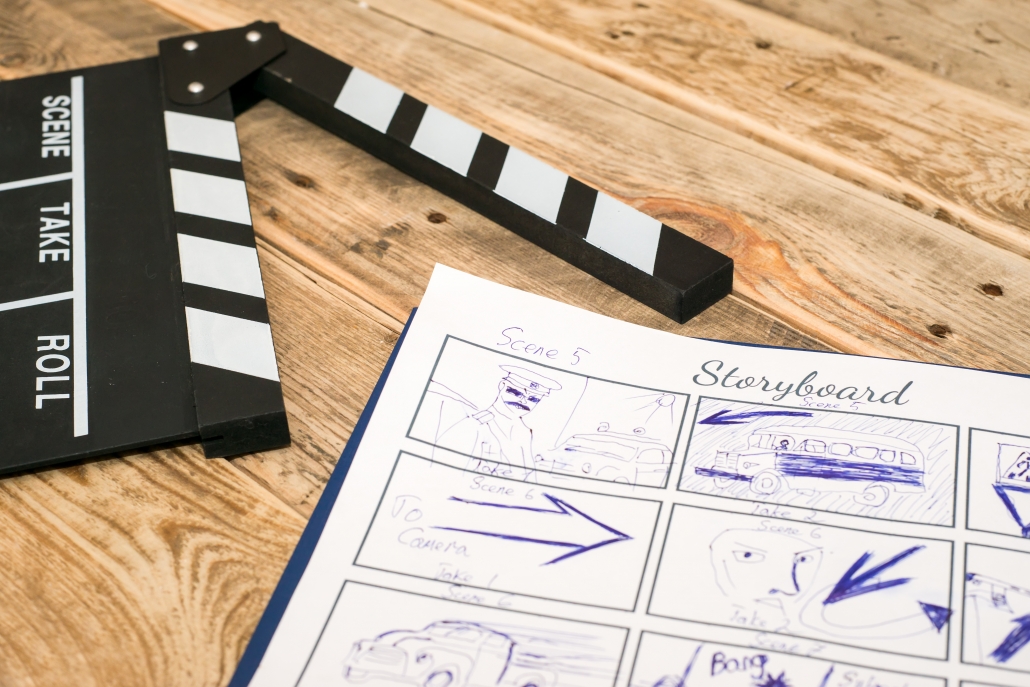 storyboarding with blue pen on paper and a film slate nearby